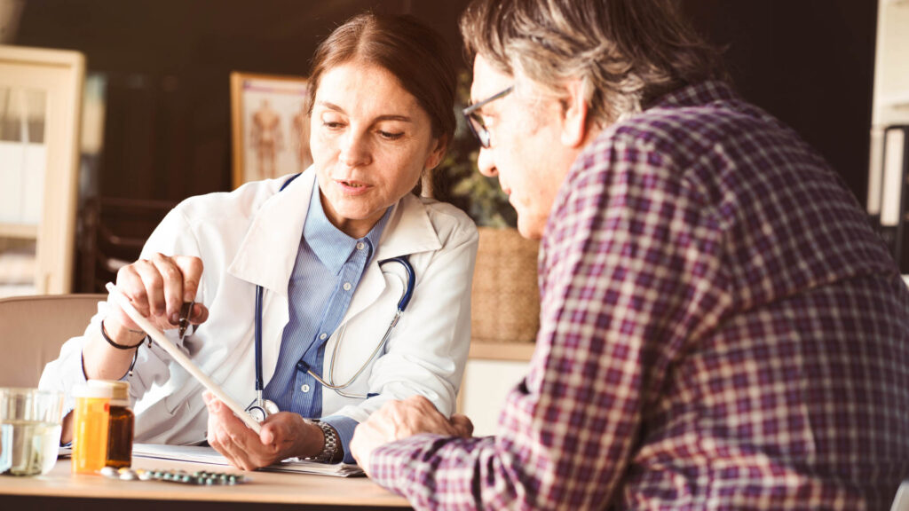 Øjenlæge taler med en patient og viser ham resultater på en tablet