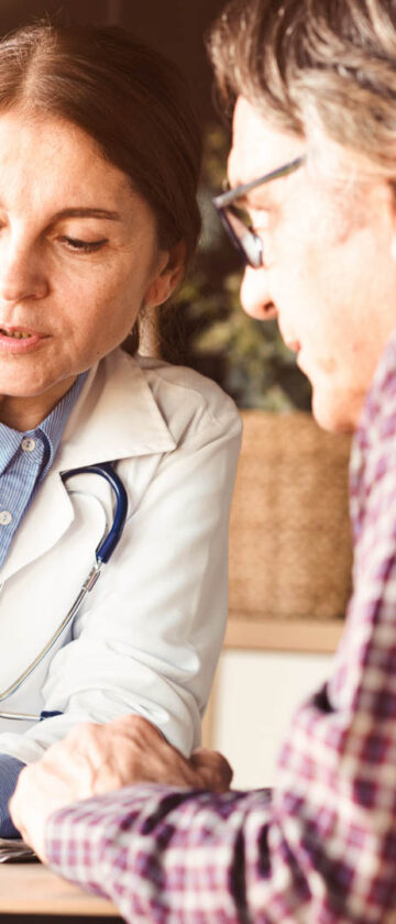 Øjenlæge taler med en patient og viser ham resultater på en tablet