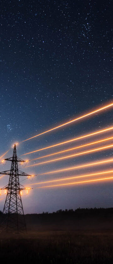 Elmaster mod nattehimmel med lysende ledninger imellem for at symbolisere energi