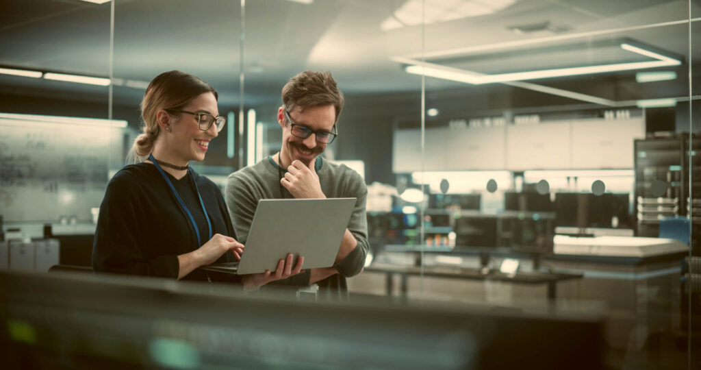 To ingeniører taler om cloud-projekt, mens de kigger på en computer