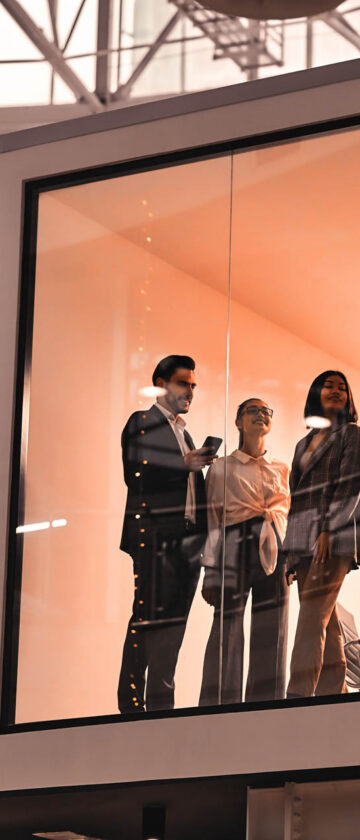 Team members discussing work in a glass-walled meeting room