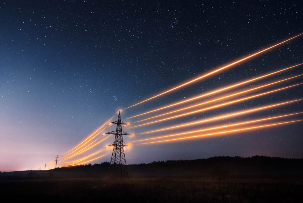 Electricity transmission towers with power lines under a starry night sky