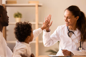 Pediatrician giving a high five to a young patient during a medical consultation
