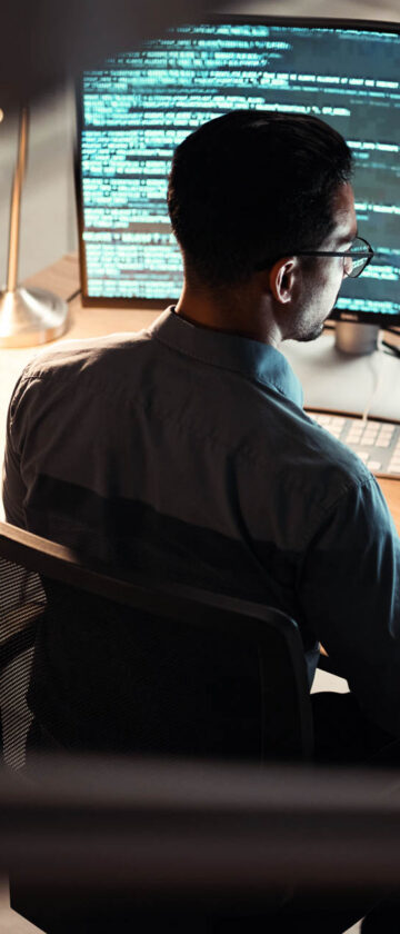 Software developer working on a laptop with code displayed on the screen