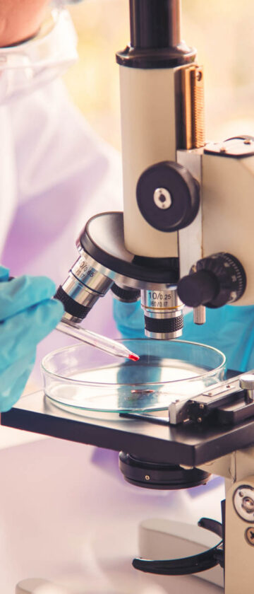 Female scientist using a microscope for medical research in a laboratory